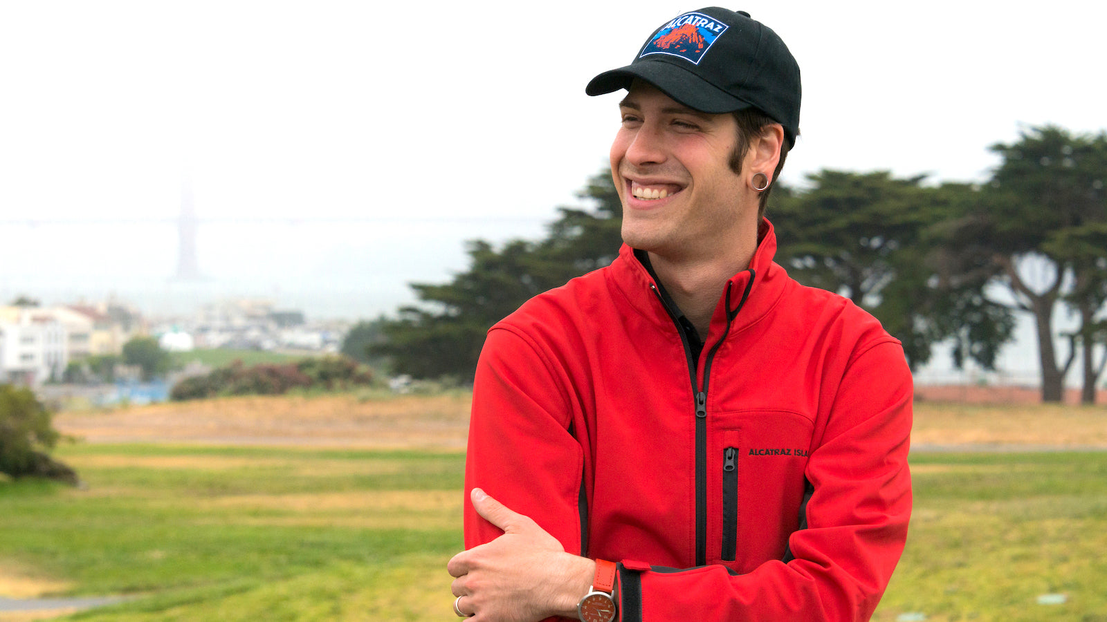 A smiling man stands in San Francisco Fort Mason's Great Meadow on a foggy day.