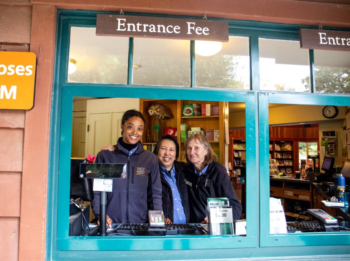 Smiling staff members welcome visitors at the Muir Woods Entrance kiosk window