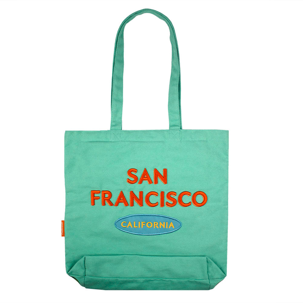 A colorful tote bag with a retro-style  San Francisco logo embroidered on a teal green bag