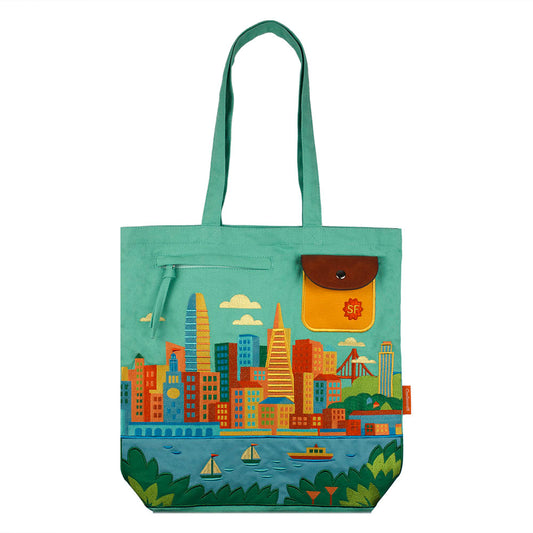 A colorful tote bag with a retro-style scene of San Francisco's city skyline embroidered on a teal green bag