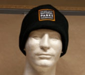 Black beanie with a patch on a mannequin head against a brown background
