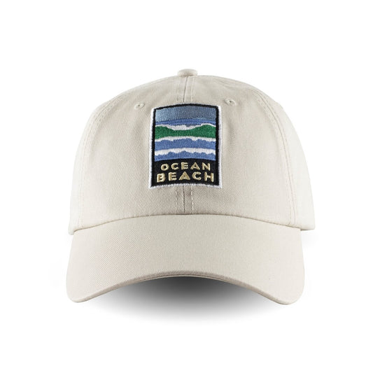 Tan baseball cap with colorful embroidered Ocean Beach logo on front panels. Artwork by Michael Schwab.